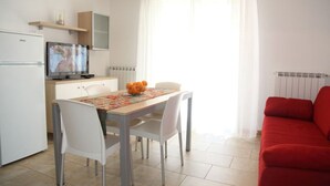 Un espacio habitable compacto con comedor, un sofá rojo, televisión y cocina.