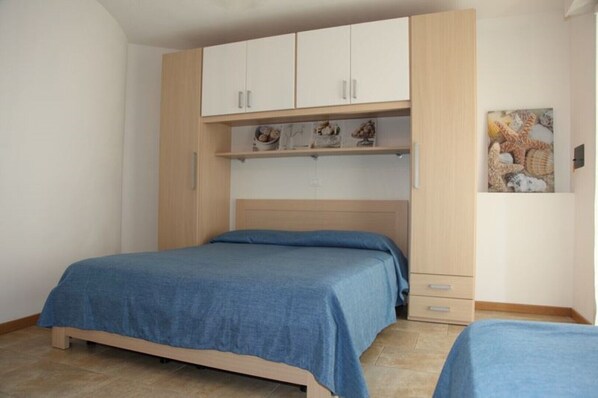 Ein Schlafzimmer mit einem Bett, einem Kleiderschrank und einem Regal mit Dekoration.