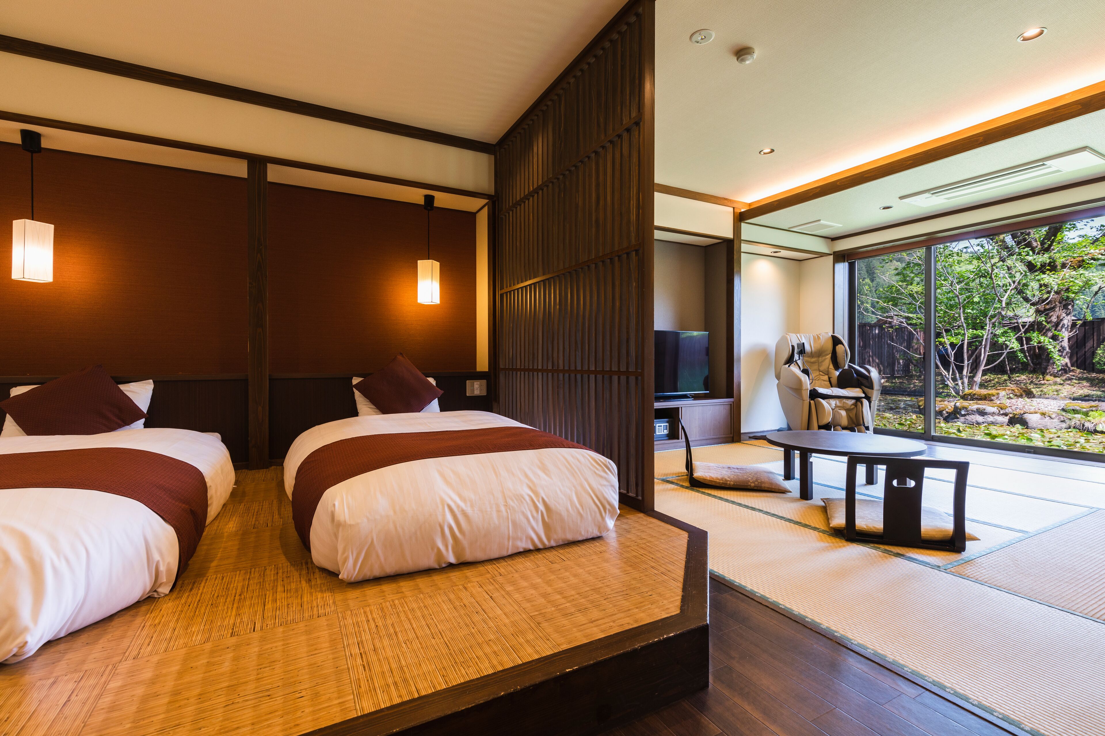 A modern hotel room with two beds, a TV, a seating area with a table, and a view of the outdoors.