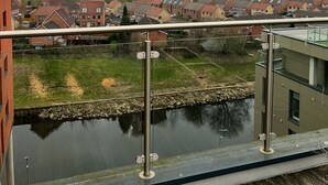 Een woonwijk met huizen, een klein waterlichaam en een modern gebouw op de achtergrond.