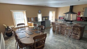 A spacious kitchen with a central island, a dining area with wooden chairs, and a large window providing natural light.