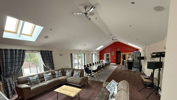 A spacious living area with a large sectional sofa, a wooden coffee table, and a red accent wall.