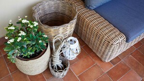 Des meubles en osier, une plante en pot et une lanterne posés sur un sol carrelé.