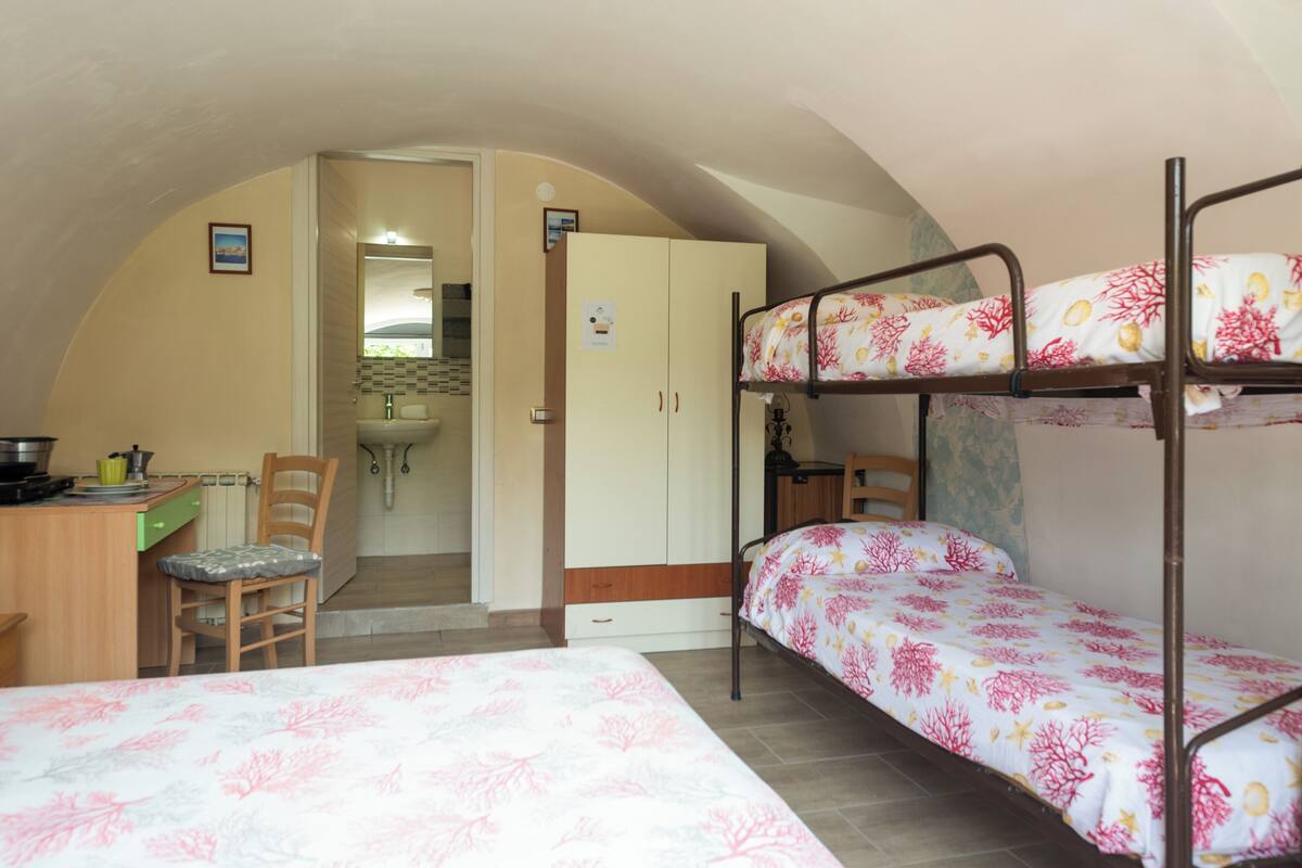 A compact room with bunk beds, a desk, and a chair.