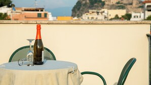 A table with a bottle and glass on a balcony overlooking a historic building. - Villa dei Sogni (Ischia)