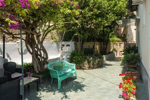 A patio with a bench, chairs, and potted plants. - Villa dei Sogni (Ischia)