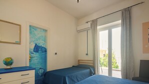 A bedroom with two beds, a dresser, a globe, and a painting of a coastal scene. - Villa dei Sogni (Ischia)