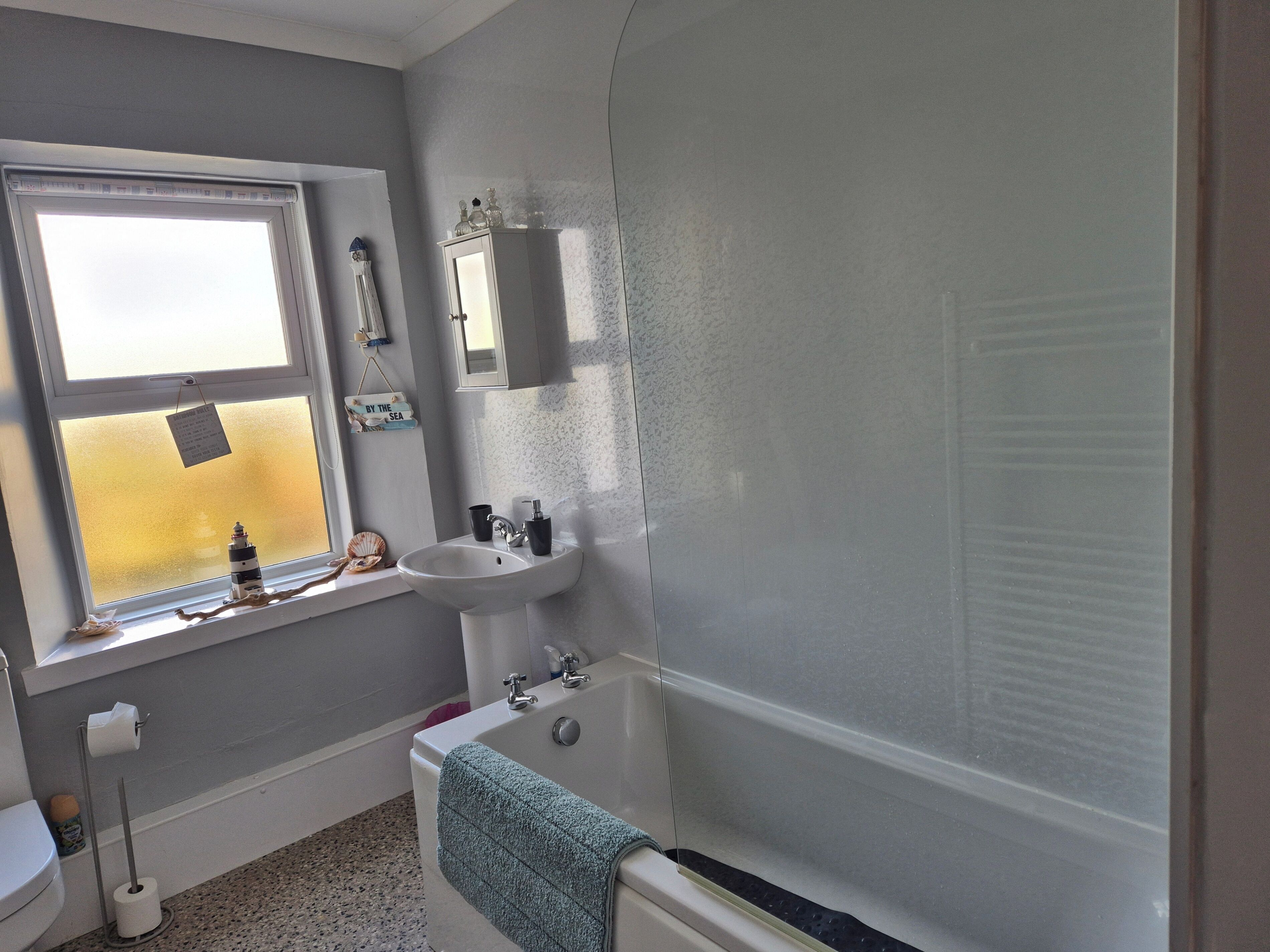 A bathroom with a window, sink, and bathtub.