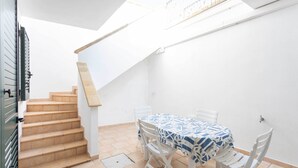 Een eetgedeelte met een tafel, stoelen, een trap en een raam.