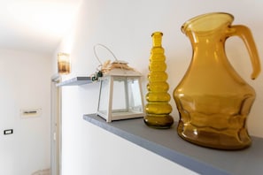 A shelf with a white lantern, a tall yellow vase, and a yellow pitcher. - APPARTAMENTI MALDIVE DEL SALENTO (Salve)