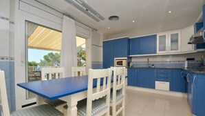 A modern kitchen with blue cabinets, white countertops, and a blue dining table with white chairs. - Beautiful villa  in Platja d´Aro with sea views and a pool (Platja d'Aro)