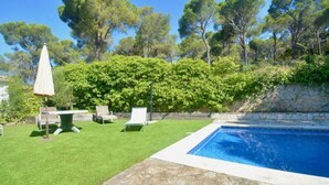 A swimming pool with a stone deck, surrounded by a grassy lawn and trees. - Beautiful villa  in Platja d´Aro with sea views and a pool (Platja d'Aro)
