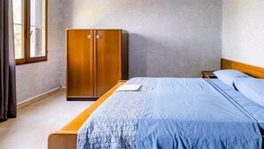 A bedroom with a bed, a wardrobe, and a window.