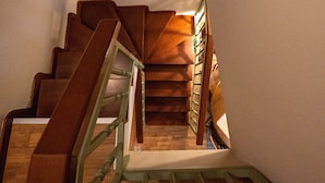 A wooden staircase with a green handrail, leading to a landing with a wooden ceiling and a green plant on the wall. - Dandy Villas Ioannina- Colorful Boutique House (Ioannina)