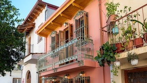 A two-story building with a balcony, potted plants, and a cobblestone street. - Dandy Villas Ioannina- Colorful Boutique House (Ioannina)