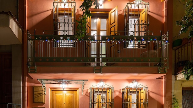 A two-story building with a wooden balcony, a wooden door, and a brick-paved entrance. - Dandy Villas Ioannina- Colorful Boutique House (Ioannina)