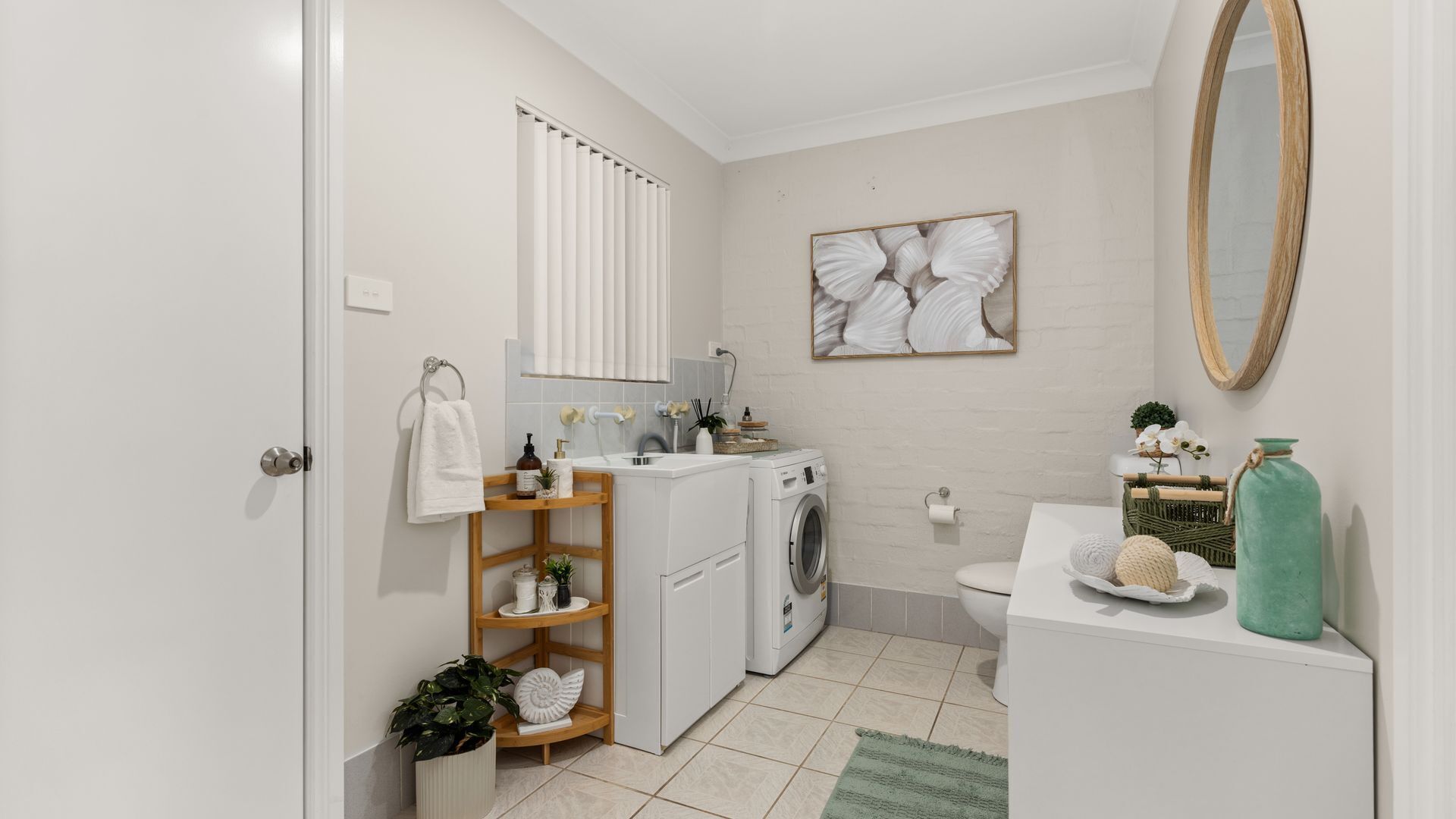 A compact bathroom with a washing machine, toilet, and a sink area.