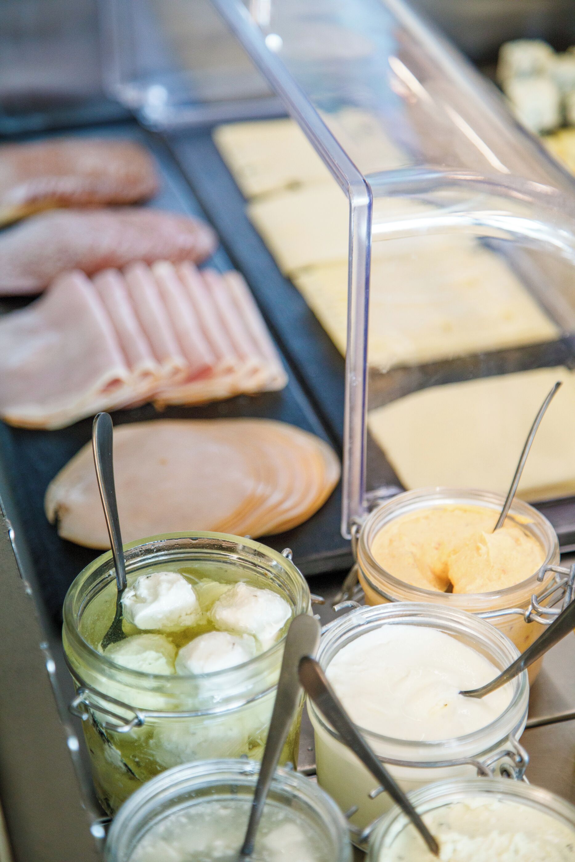 Mostrador de delicatessen con diferentes carnes y acompañamientos.