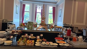Ein reichhaltiges Buffet mit verschiedenen Speisen, einer Salatbar und einer dekorativen Eiffelturm-Mitteldecke.