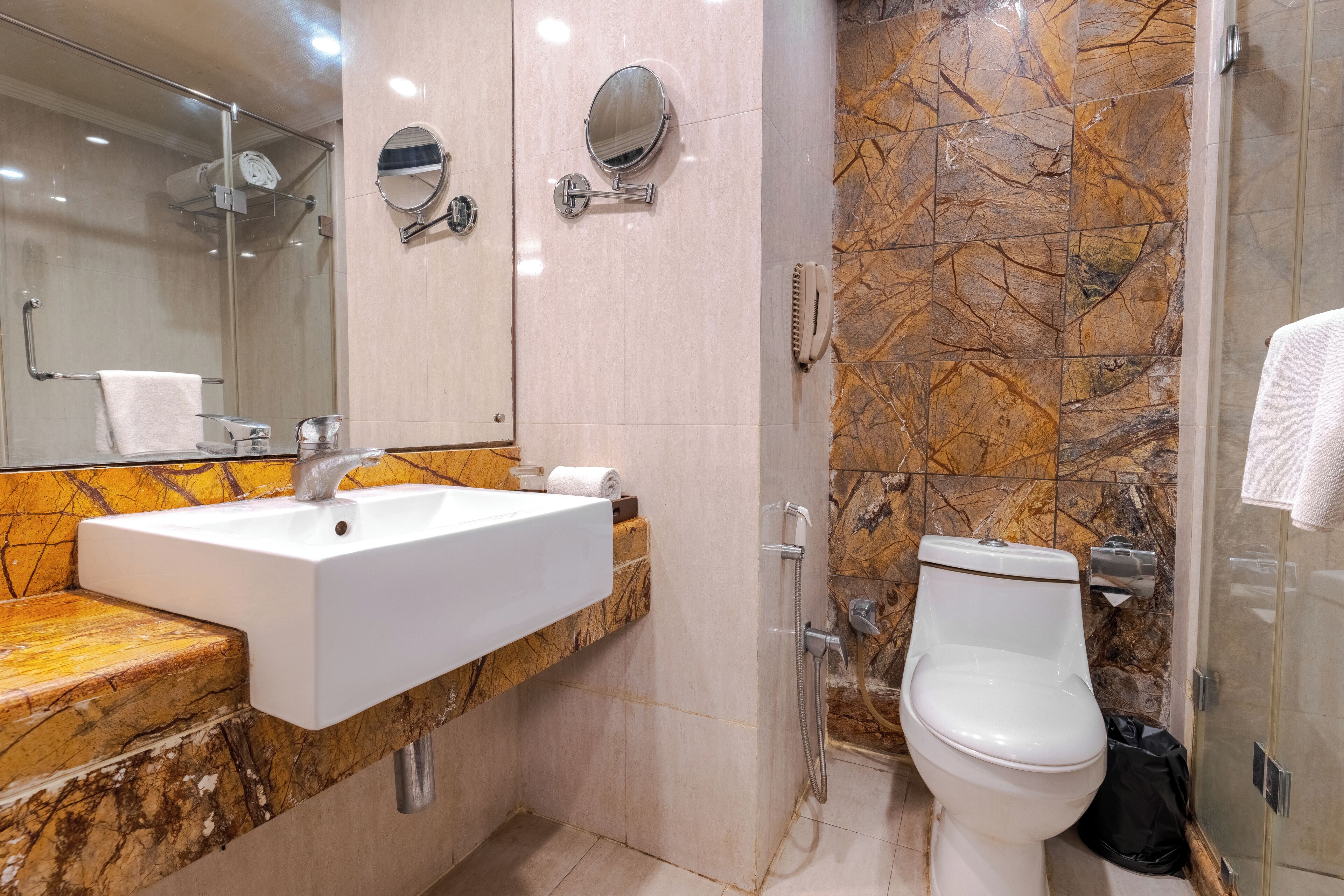 A bathroom with a sink, mirror, toilet, and shower.