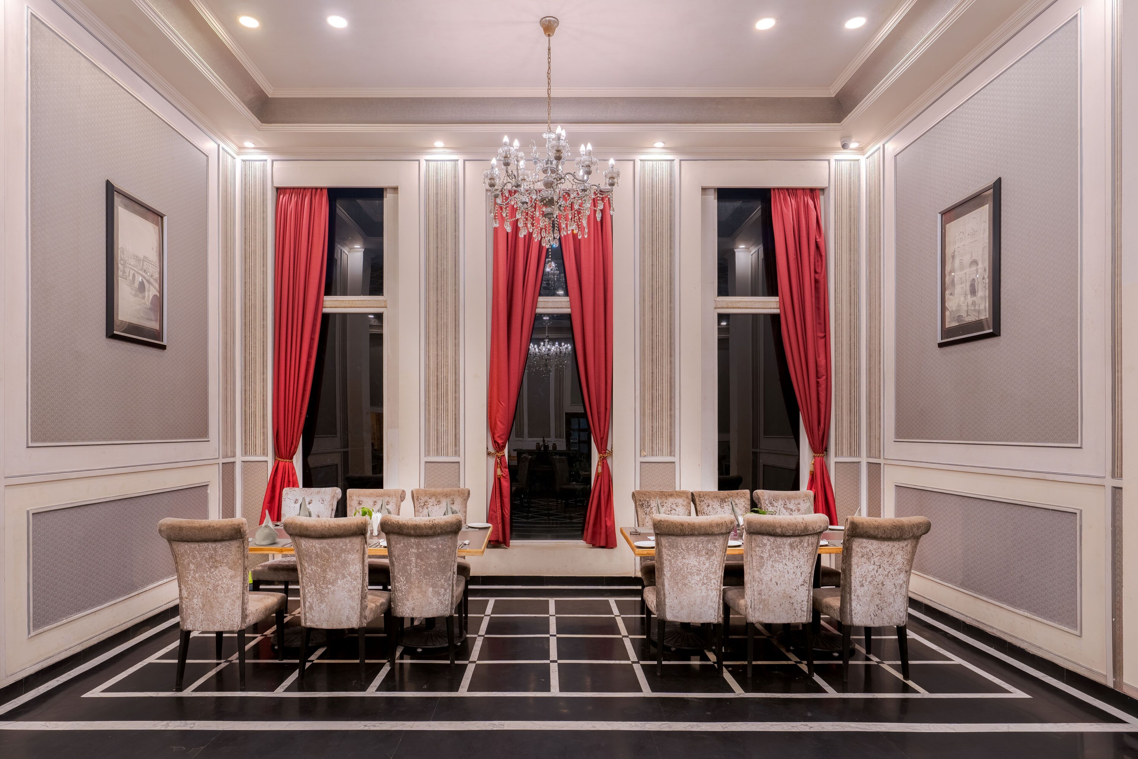 Uma sala de jantar formal com um candelabro, cortinas vermelhas e quadros nas paredes.