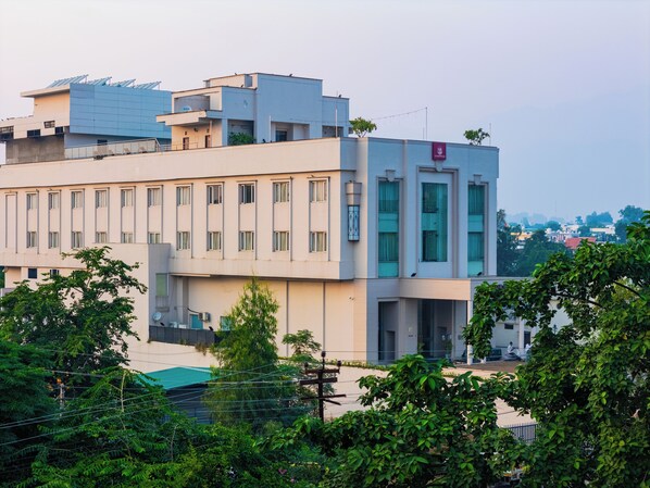 A multi-story building with a flat roof, large windows, and a sign indicating a medical facility. - Hotel Blue Saphire Countryside  (Haldwani)