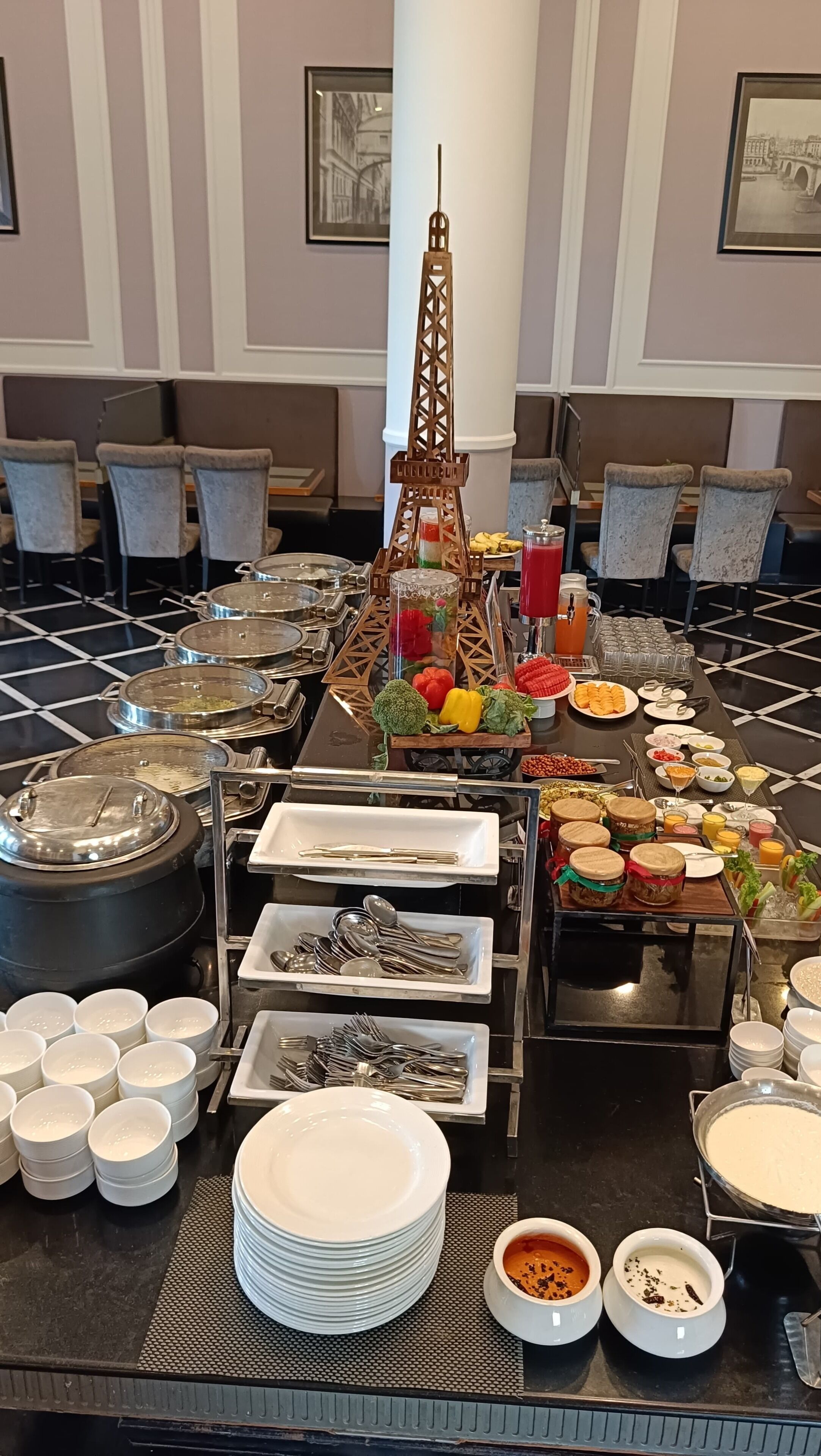 Disposición de bufé con diferentes alimentos, utensilios y una decoración con la Torre Eiffel.