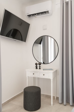 A bathroom with a white vanity, a round mirror, a flat-screen TV, and a grey curtain. - Dioni Villa Mykonos (Mykonos)