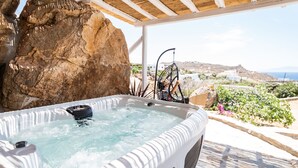 Un jacuzzi con vistas a un paisaje rocoso y una silla colgante.