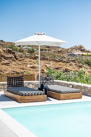 A poolside area with two wooden loungers and a white umbrella. - Dioni Villa Mykonos (Mykonos)