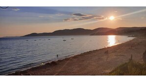 Una playa con barcos en el agua y montañas al fondo.