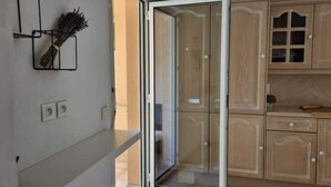 Una cocina con armarios de madera, una puerta corrediza de vidrio y una lámpara fijada a la pared.