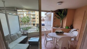 Un balcón con un sofá, una mesita y sillas. Se observa un edificio al fondo.