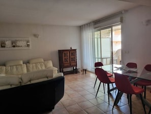 Una sala de estar con un sofá, un aparador y un comedor con sillas y una mesa.