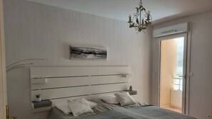 Un dormitorio con cama, mesita de noche, cuadro en la pared y candelabro.