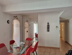 Un comedor moderno con una mesa de vidrio y sillas rojas, un reloj en la pared y un adorno decorativo.