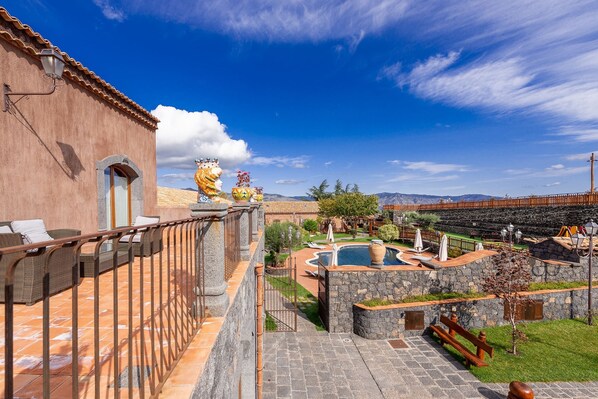 A courtyard with a swimming pool, stone walls, and a view of mountains. - Etna Quota Mille Boutique Hotel, Typical Sicilian Food & Wine (Randazzo)