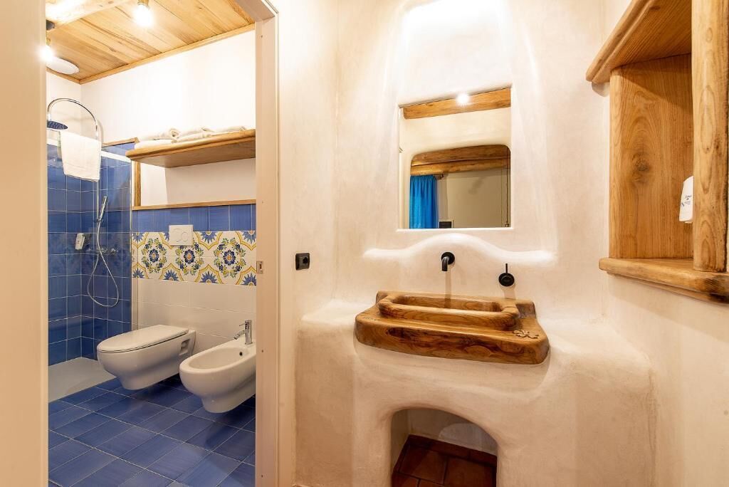 A bathroom with a white sink, a mirror, and a blue-tiled shower area.