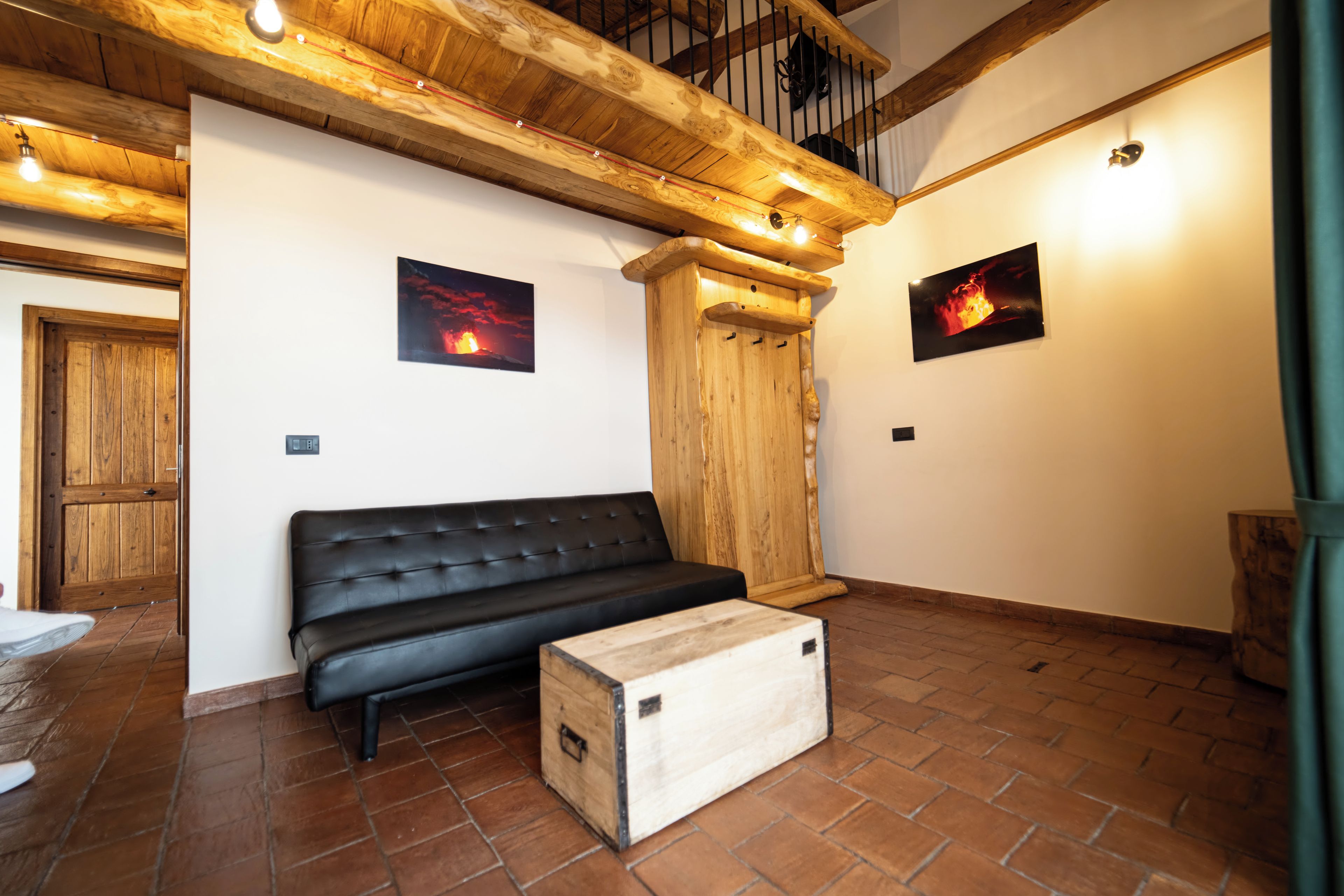 Um quarto com um sofá de couro preto, paredes de madeira e piso de azulejos.