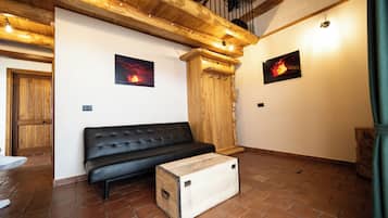 Um quarto com um sofá de couro preto, paredes de madeira e piso de azulejos.