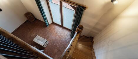 A wooden staircase with a view of a brick floor and a window with curtains.