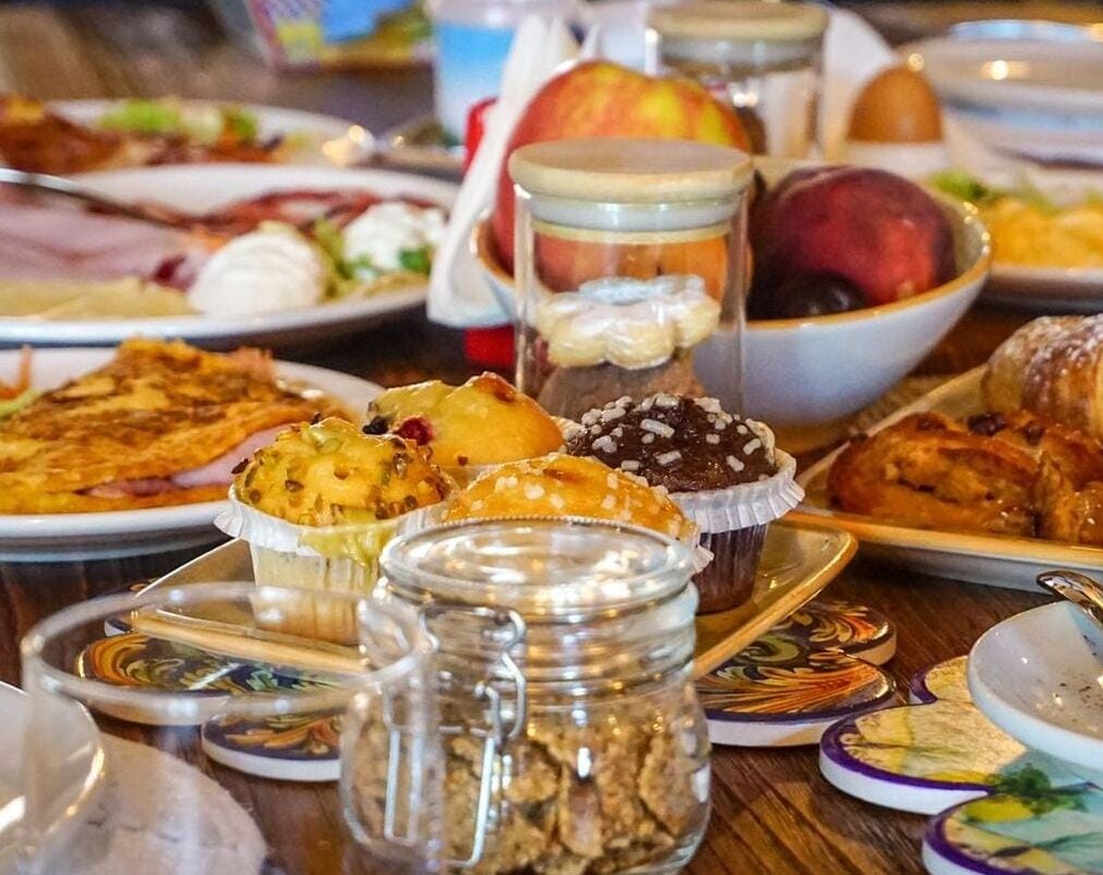A table with various dishes, including pastries, fruits, and a bowl of soup.