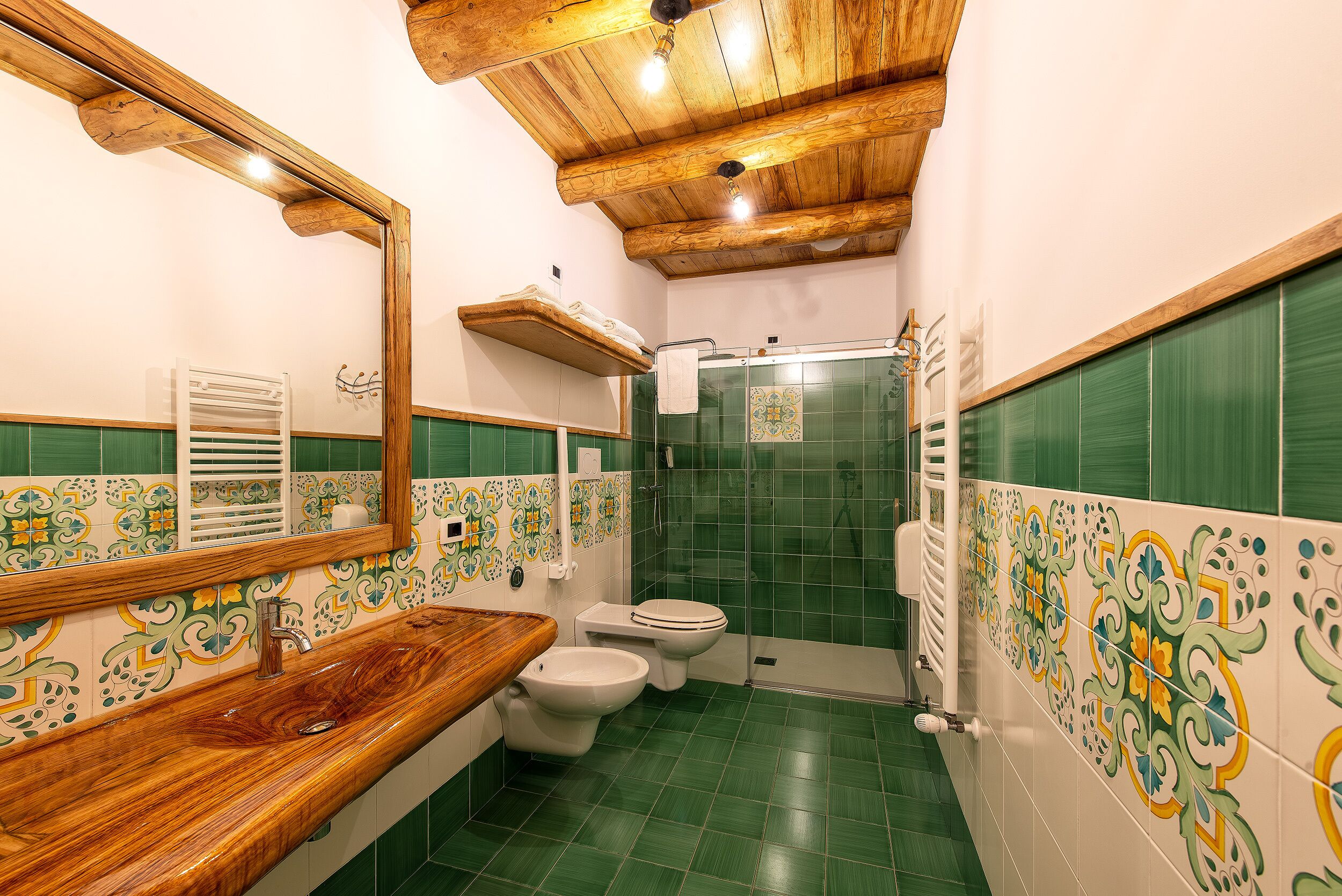A bathroom with a wooden vanity, a white sink, a toilet, and a shower area.