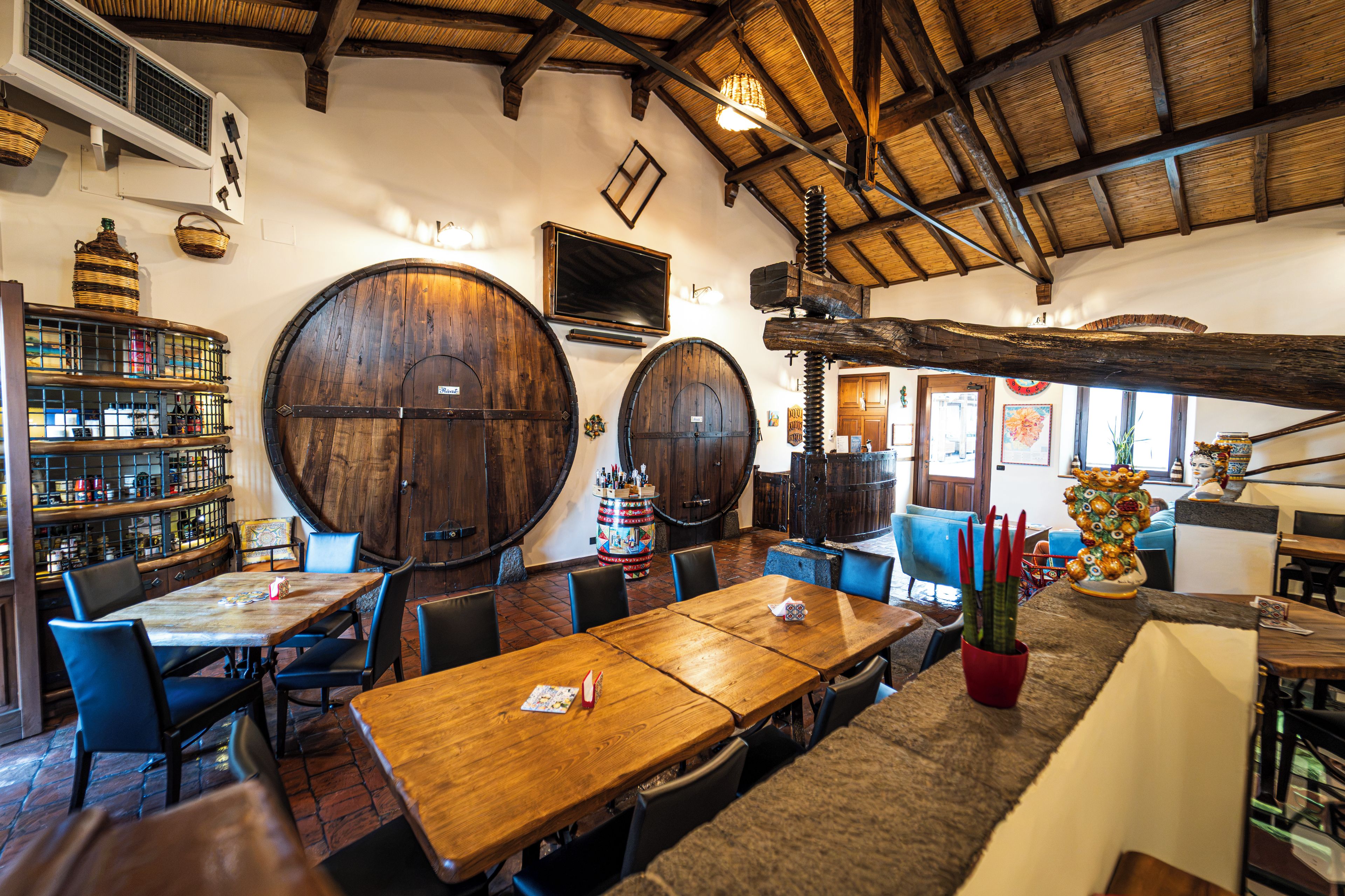 A rustic interior with wooden barrels, a bar area, and a dining space with tables and chairs.