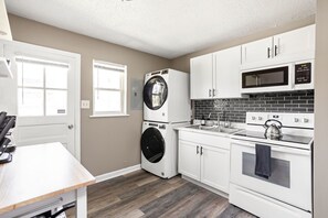 Une cuisine compacte équipée d’un lave-linge, d’un four à micro-ondes, d’un four et d’un évier.