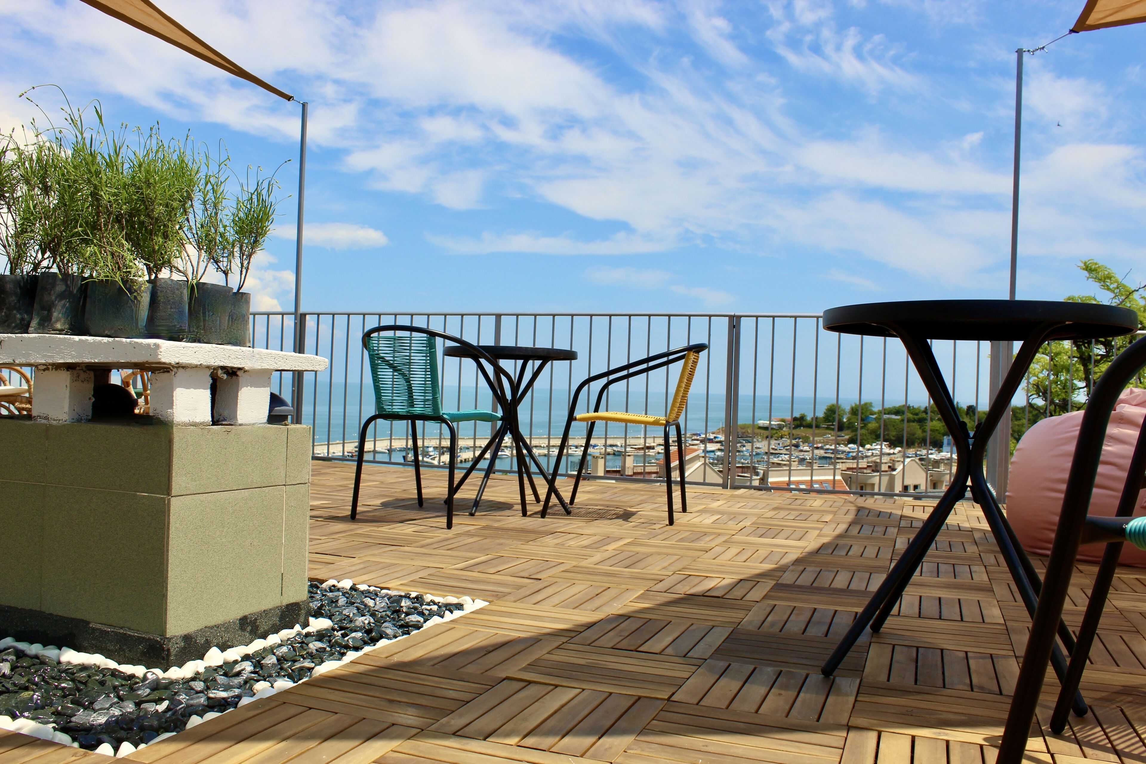 Une terrasse en bois avec une rambarde, des sièges d’extérieur et des plantes en pot.