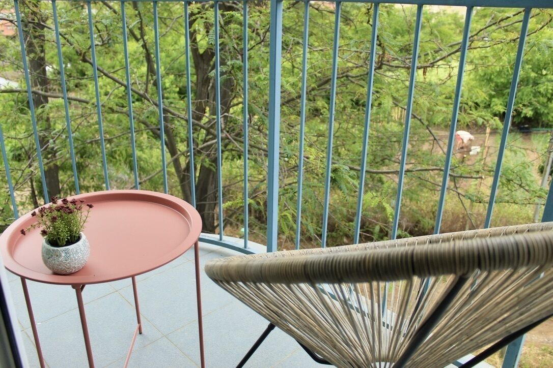 Un balcon avec une chaise en osier et une petite table sur laquelle est posée une plante en pot.