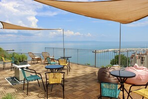 A terrace with outdoor furniture, a view of the sea, and a railing. - SUNSET ART HOTEL (Sozopol)