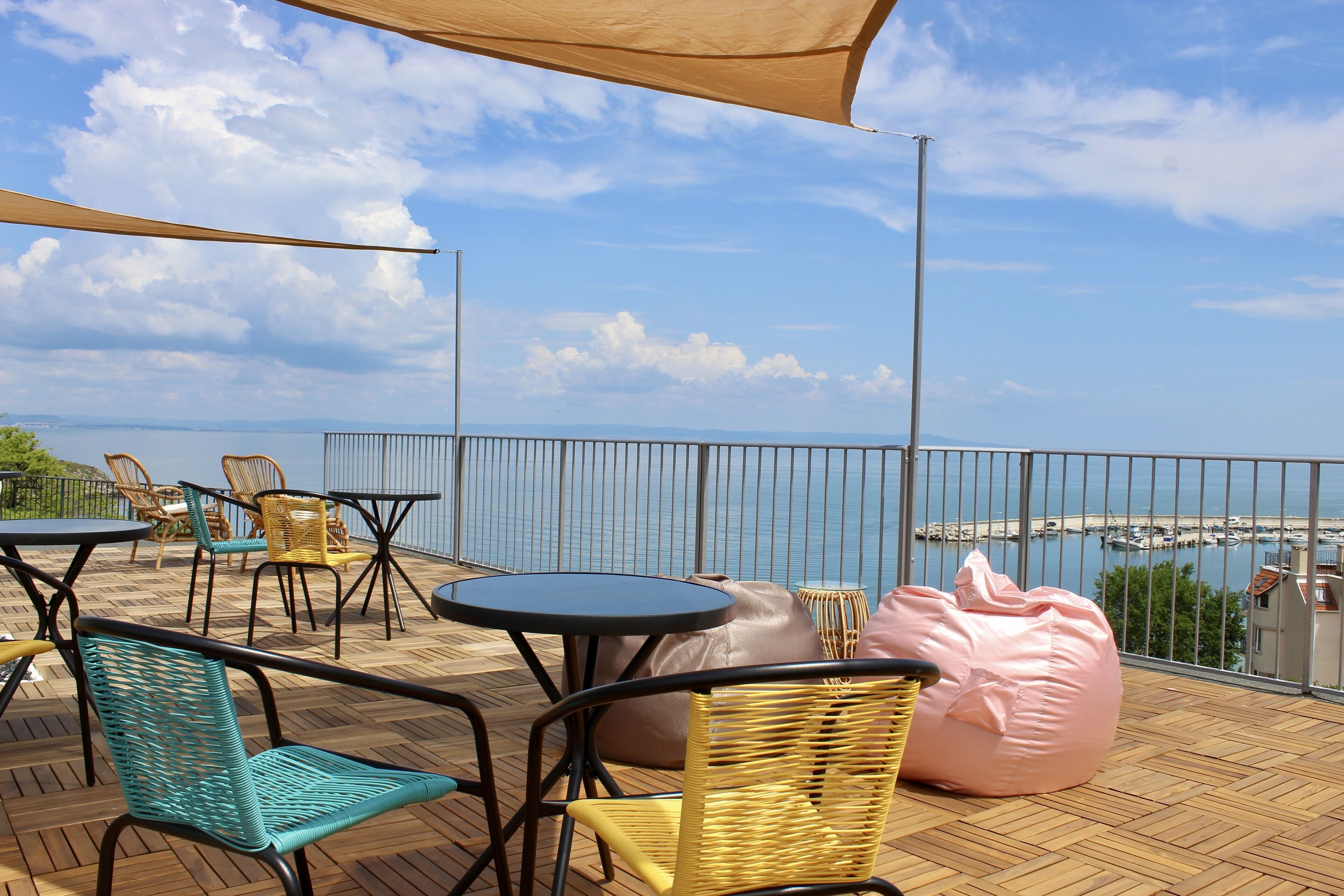 Een terras buiten met rieten meubels, een tafel en uitzicht op zee.
