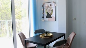 A dining area with a table, chairs, and a wall-mounted light fixture. - SUNSET ART HOTEL (Sozopol)